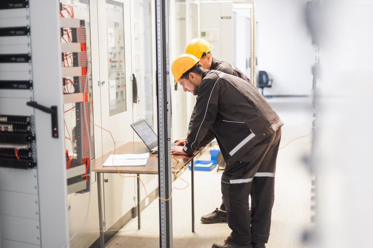 Two workers looking at computer hooked up to electrical hub