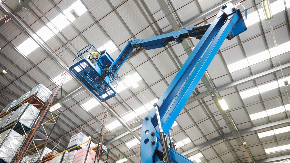 Blue crane lifting up worker to lighting in warehouse